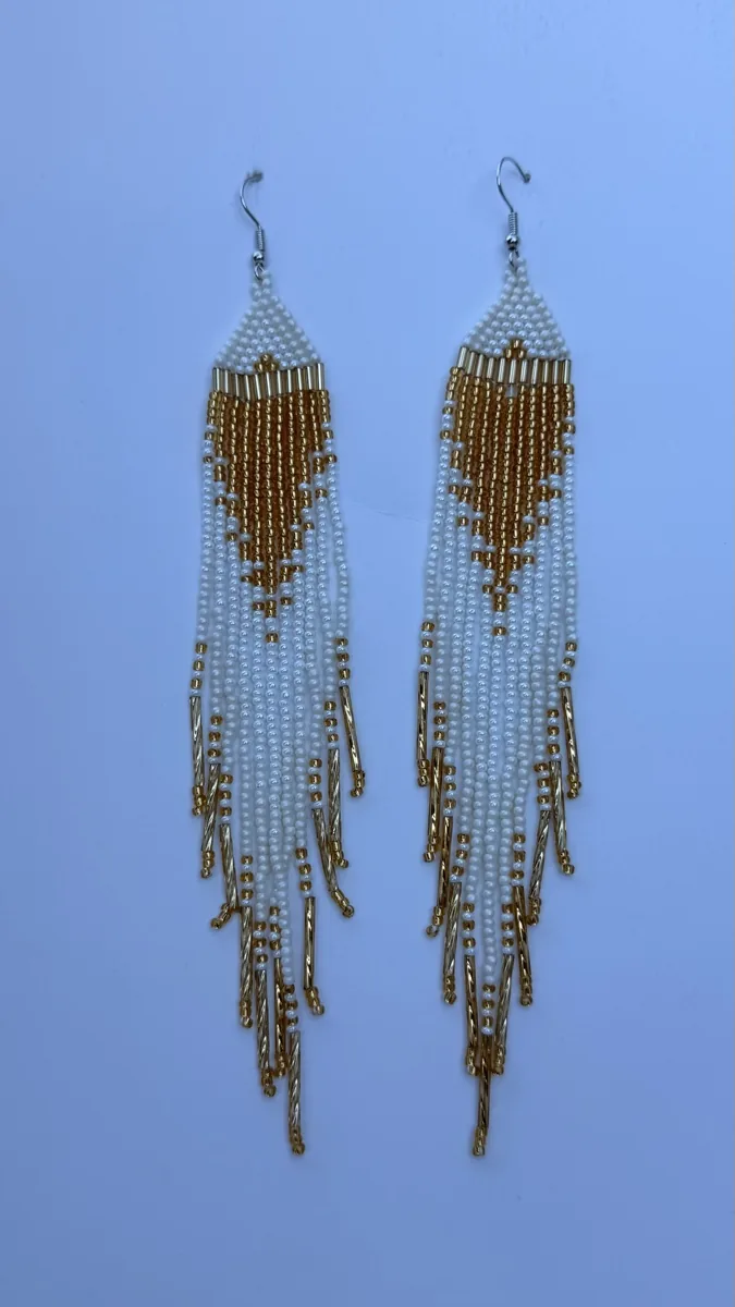 Pair of white beaded drop earrings with gold heart motif and fringe.