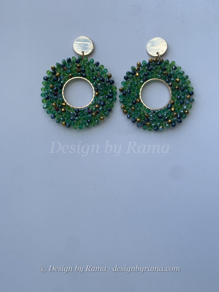 Large open circle hoop earrings densely covered in mixed green and iridescent dark navy faceted crystals, gold disc stud top.