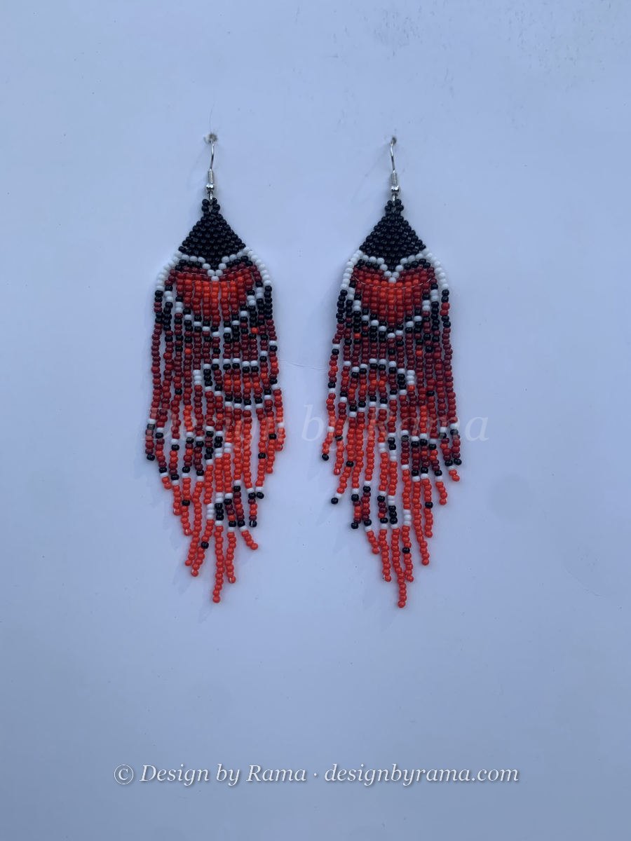 Long fringe earrings with bold orange-red and white geometric chevron stripes through a black body, staggered strand ends, wire hook.