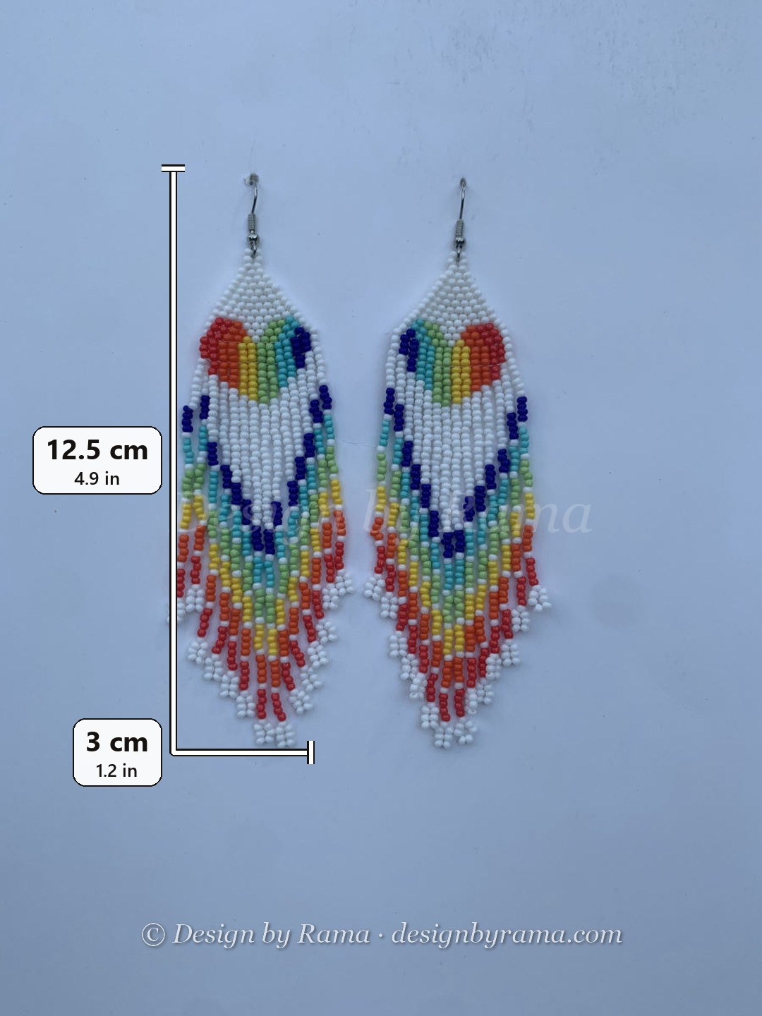 Long fringe earrings with rainbow heart motif on white bead ground, multicolour cascading fringe in orange, yellow, green, blue and red, wire hook.